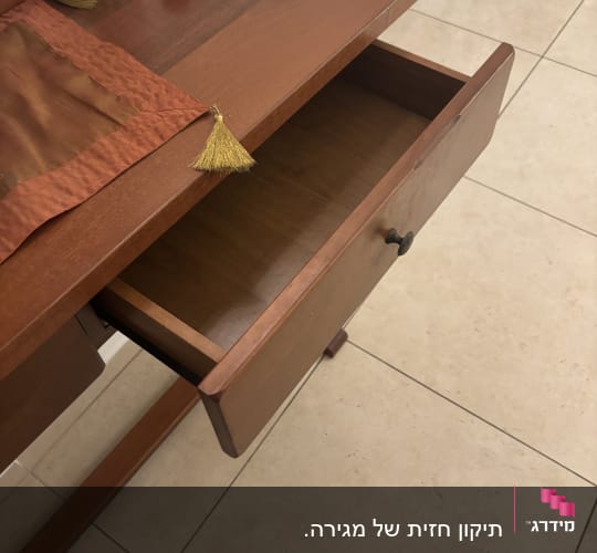מגירה פתוחה בשידה מעץ על רצפת אריחים